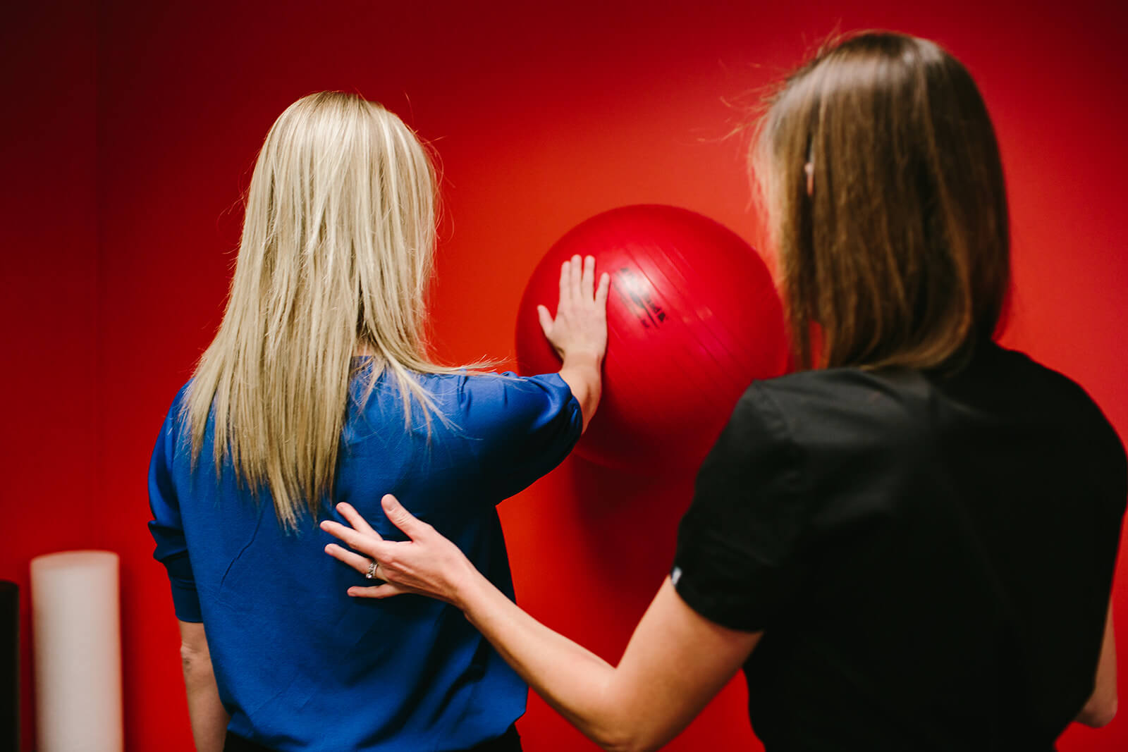 female physical therapist walking patient through yoga ball exercises for post shoulder surgery 
